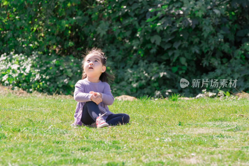 秋天午后坐在草坪上玩耍的女孩