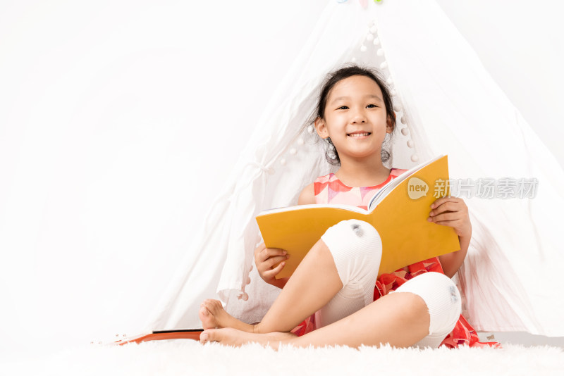 坐在白色帐篷内读书的女孩