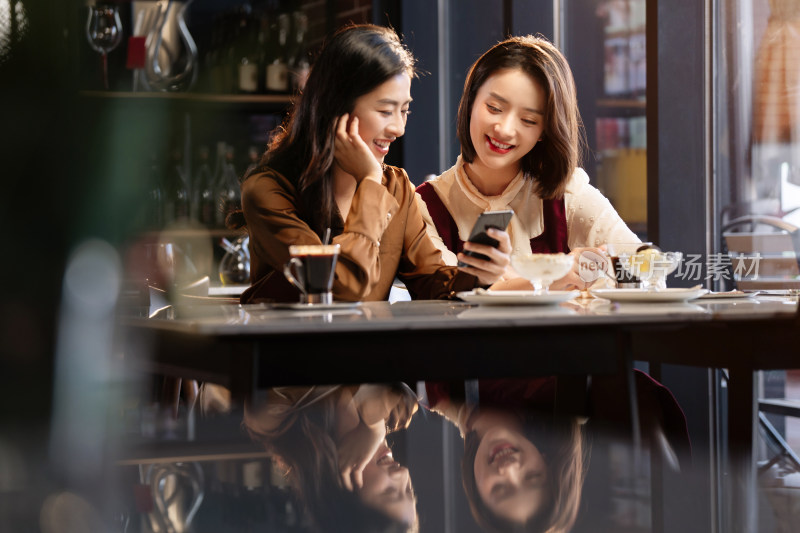 年轻闺蜜在咖啡馆使用手机