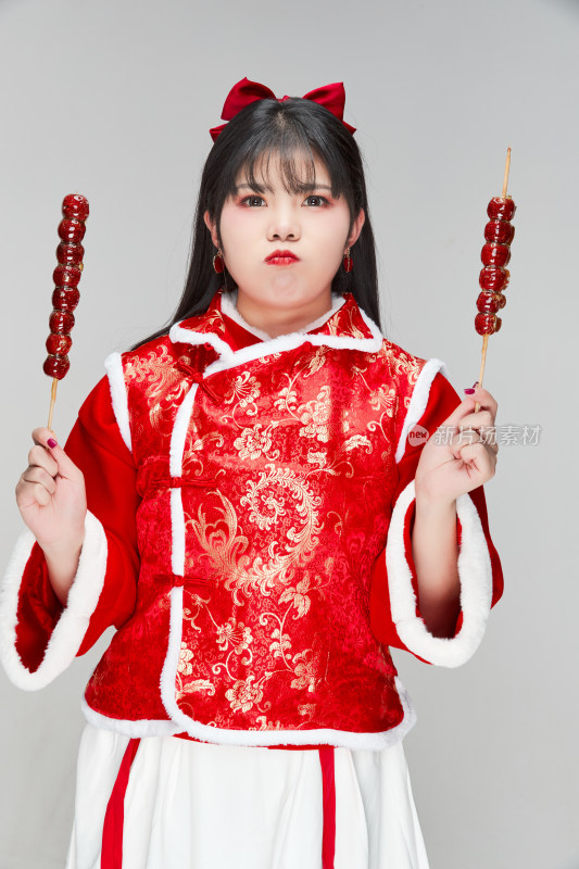 身穿喜庆服饰手拿糖葫芦吃的可爱亚洲少女