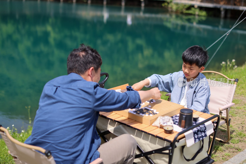 在湖边下围棋的父子