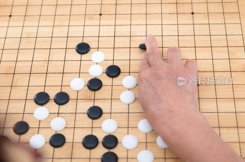 俯视拍摄手拿围棋棋子在棋盘上落子