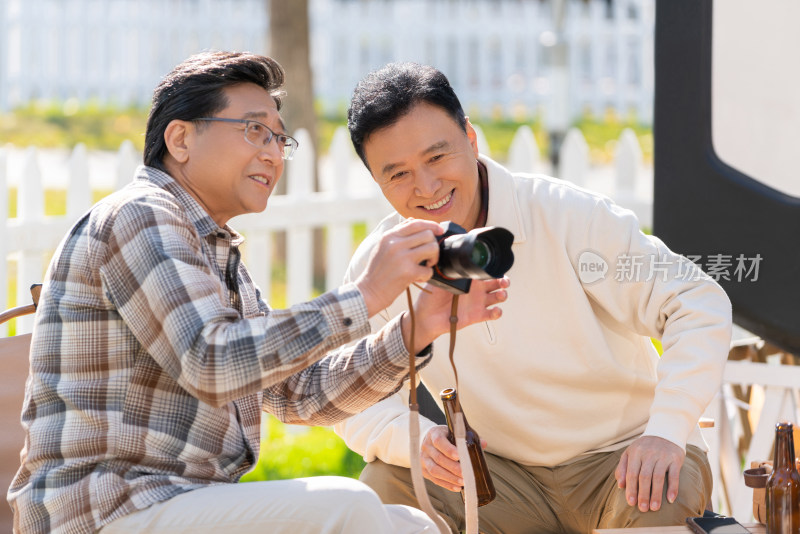 两个老年男人坐在露营地看数码相机