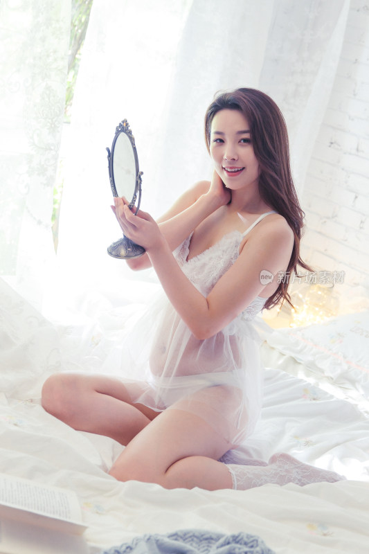 漂亮性感的青年女人坐在床上照镜子