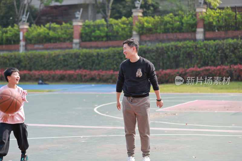 亚洲父亲和儿子在篮球场打篮球