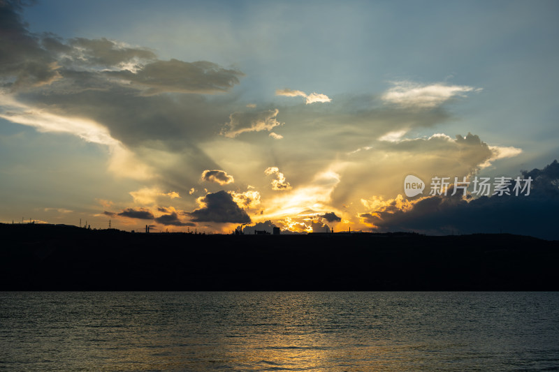 水面上空夕阳透过云层景象