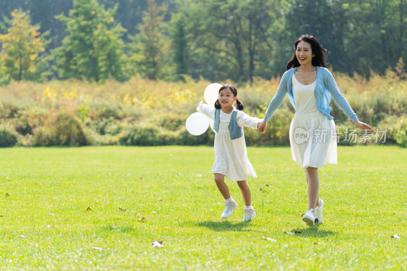妈妈和女儿拿着气球在草地上奔跑
