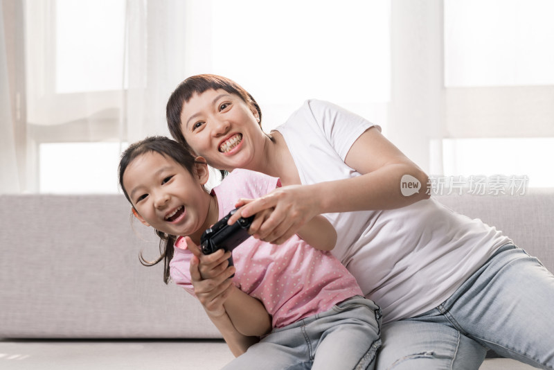 坐在沙发上玩电子游戏的中国母女