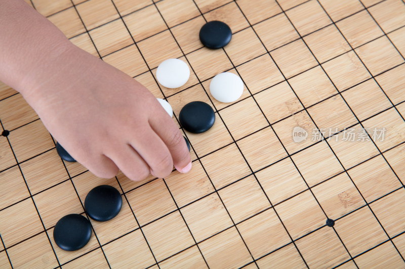 中国孩子的小手拿着棋子在围棋棋盘上下棋