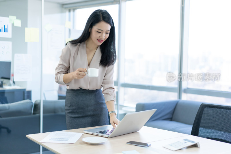 年轻商务女士在办公室喝咖啡