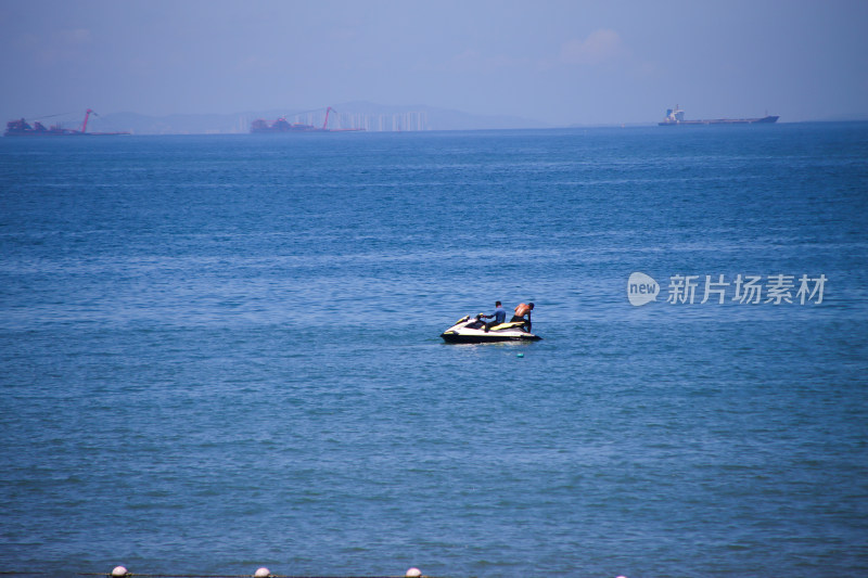 晴朗的天气，海上行使的摩托艇载着两人。