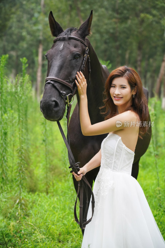 草丛中漂亮的青年女人牵着马