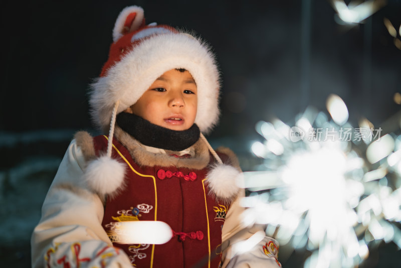 中国农历春节穿传统服饰的小男孩夜晚放烟花