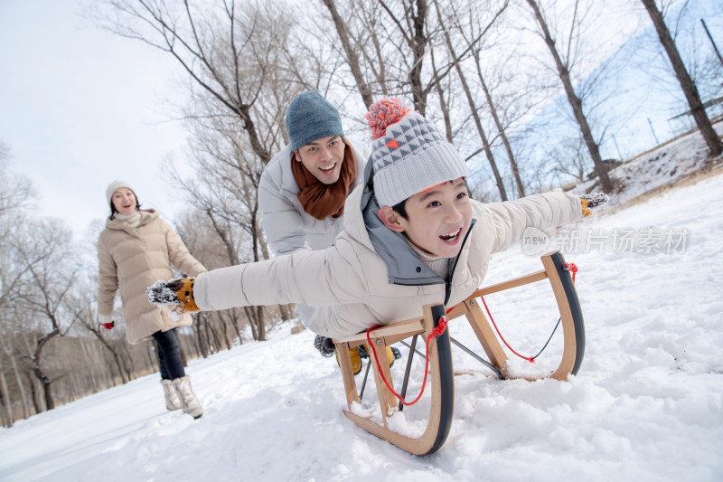 在雪地上玩雪橇的一家人