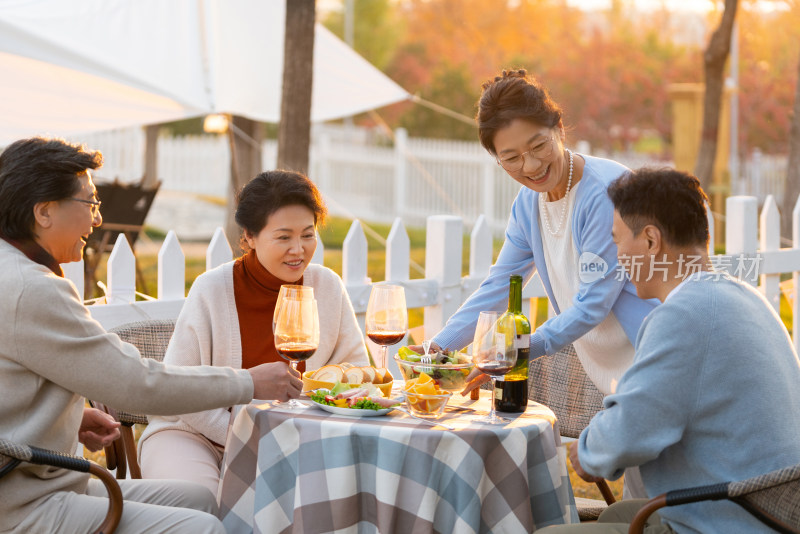 夕阳下中老年朋友在庭院里聚会喝酒聊天