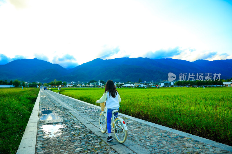 女孩骑车经过田间小道