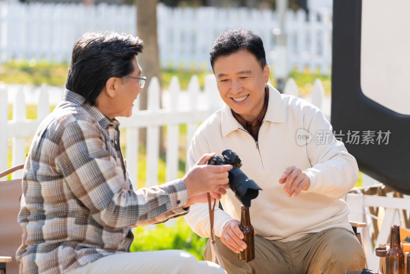 两个老年男人坐在露营地看数码相机