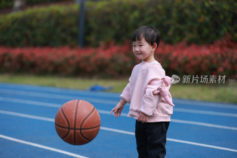 可爱的女孩在田径场上玩篮球