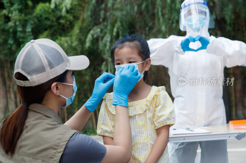 社区志愿者帮小女孩戴口罩