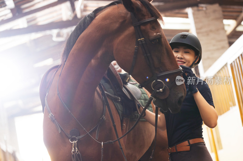 关爱马的漂亮年轻女人在马厩走廊