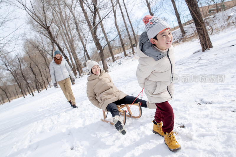 在雪地上玩雪橇的一家人