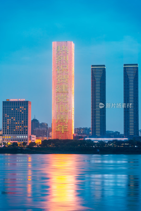 水边三栋高楼夜景，中间楼灯光色彩绚烂