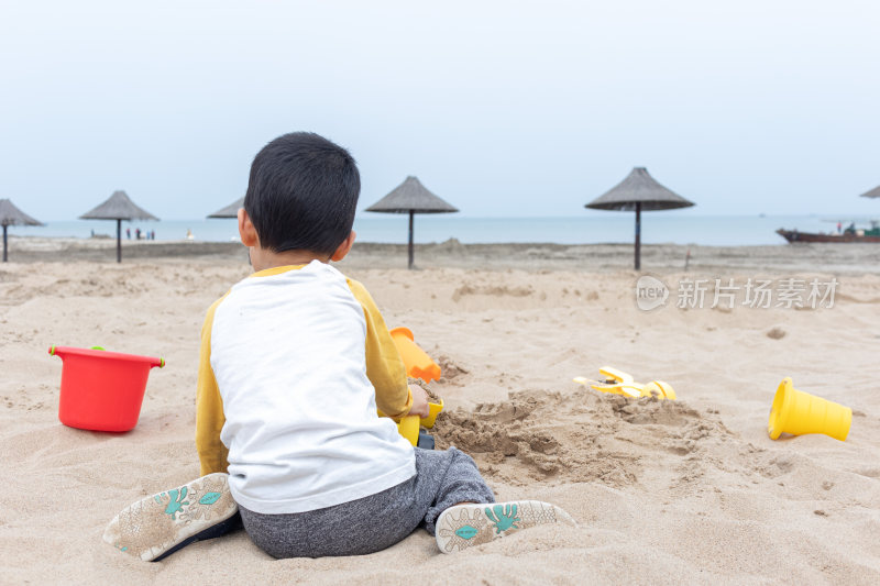 快乐的小男在海边玩沙子