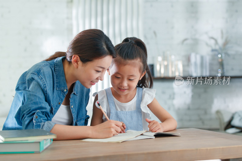 辅导女儿做作业的青年女人