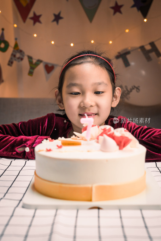 中国女孩凝望着的生日蛋糕