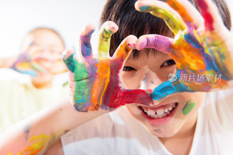 手上涂满颜料的小学生手比爱心