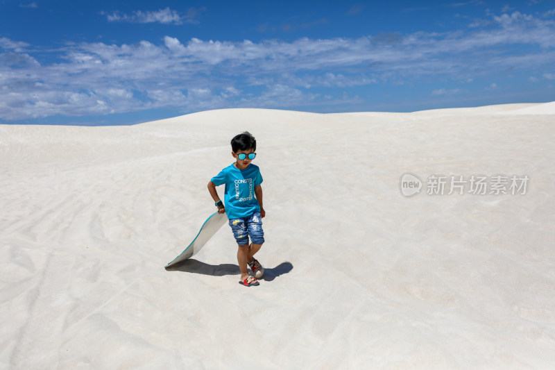 在白沙漠上玩滑板的中国小男孩