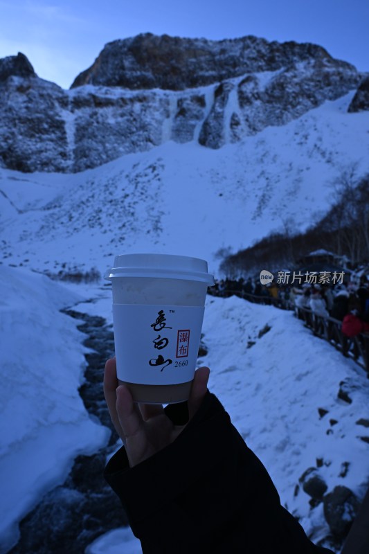 雪山上手持饮品杯的画面