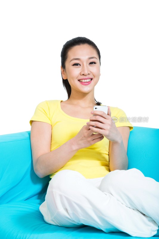 棚拍年轻女人坐在沙发上玩手机