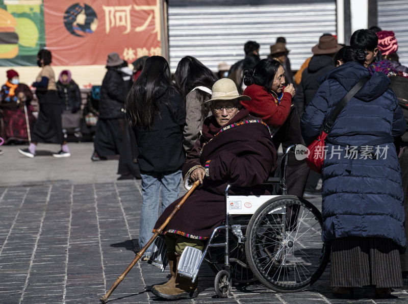 坐轮椅的老人在户外人群中拄着拐杖