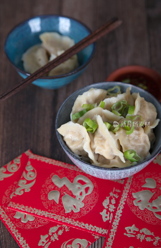 桌子上一碗饺子和蘸料红包及茶水