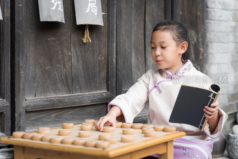 穿中国传统服饰下中国象棋的中国女孩