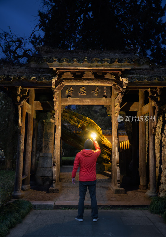 穿红色外套的人在时思寺寺院门前打灯