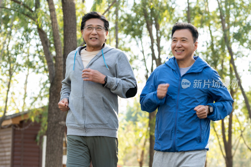 两戴运动手表的中老年男人在树林里跑步健身