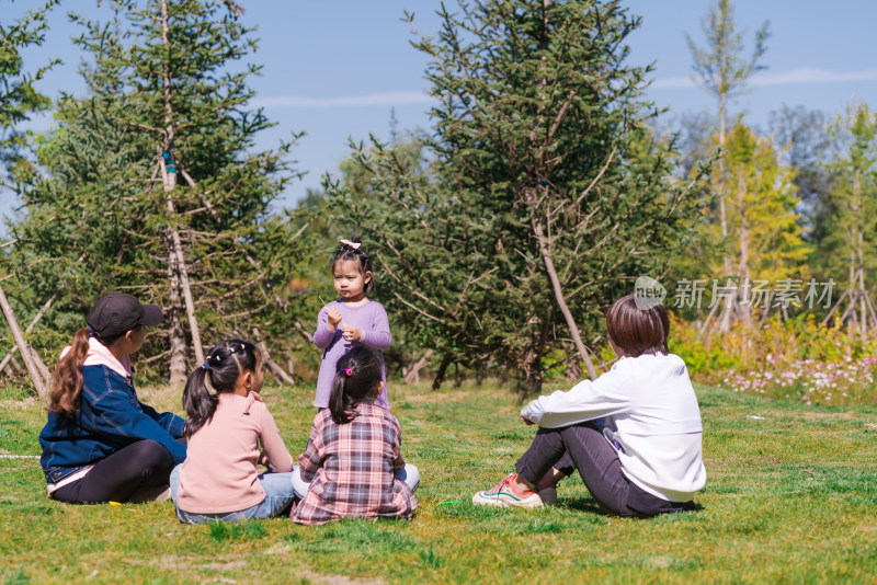 秋天午后围坐在草坪上玩耍的母亲和女孩