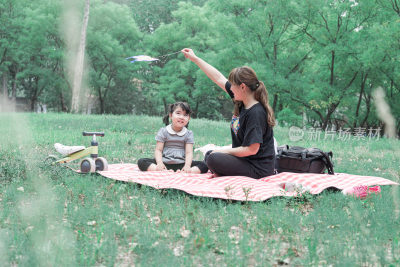 坐在公园草坪上玩耍的中国母女