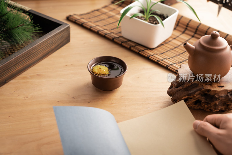 木质书桌上的紫砂壶和一杯茶