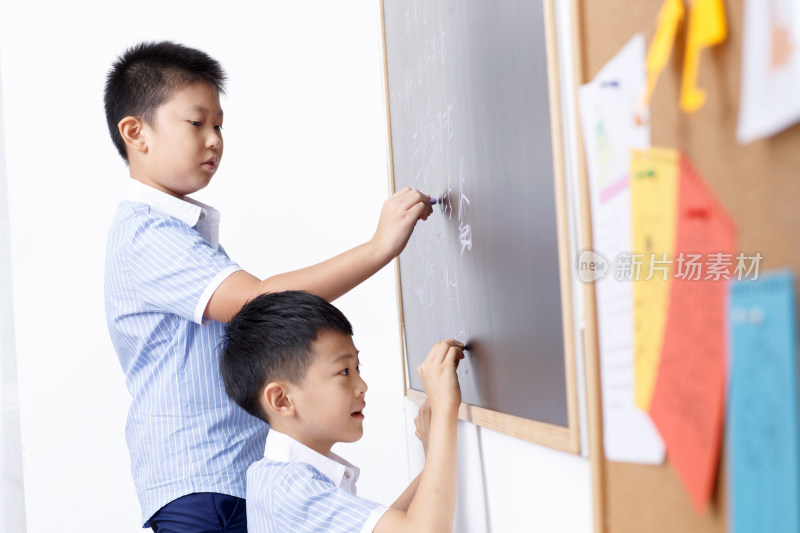 小学男生在黑板上写字