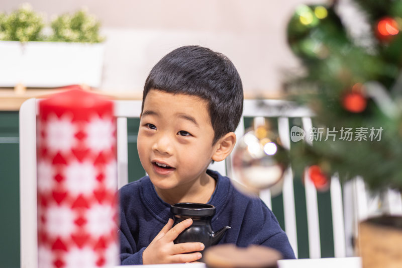一个小男孩坐在圣诞节装饰桌旁
