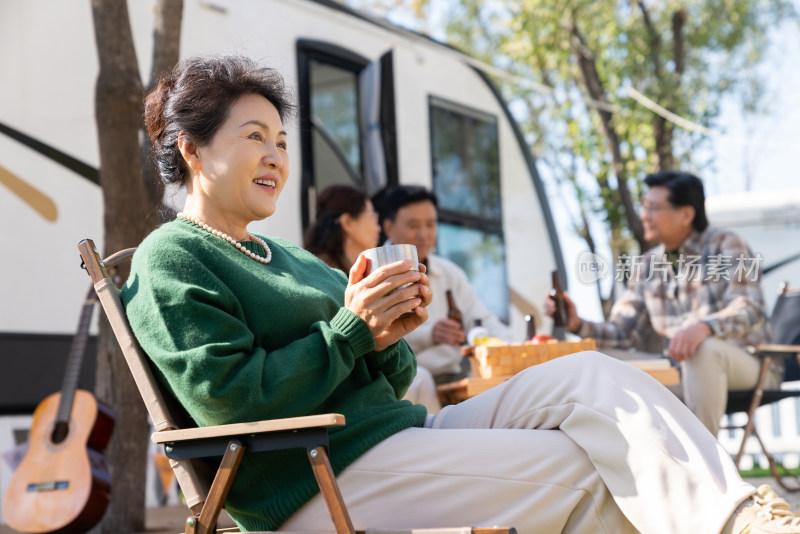 一个老年女人坐在房车露营地喝咖啡