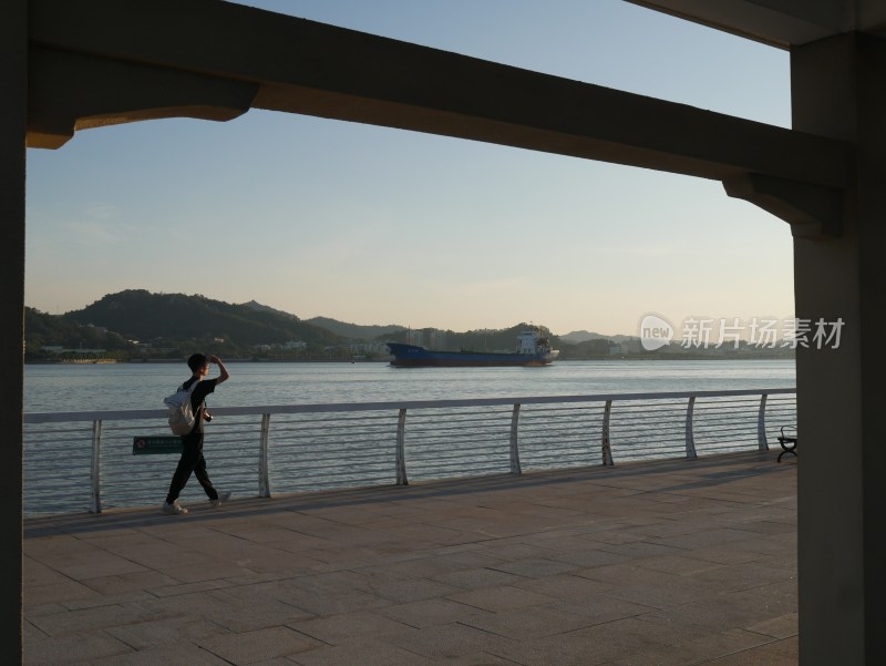 男子江边步道行走远望江景