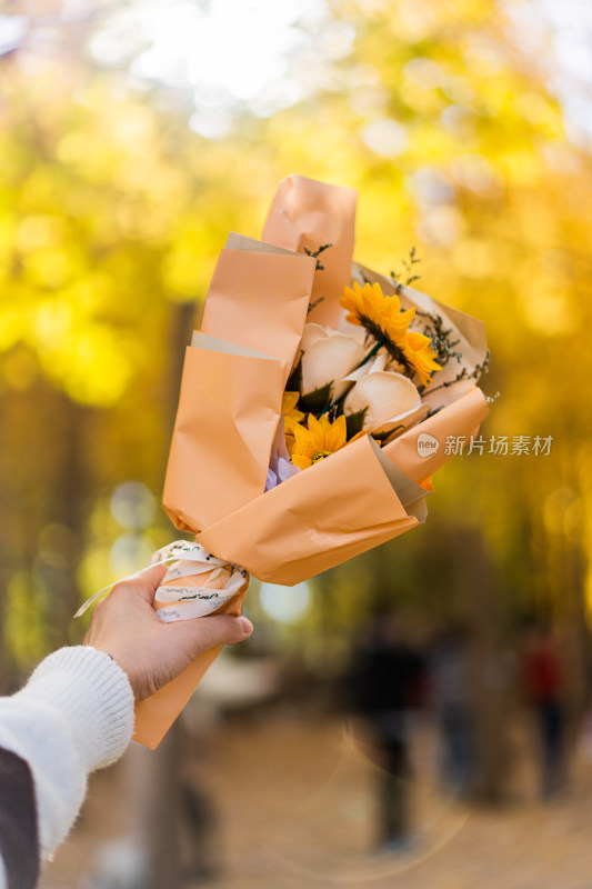 手捧花束的特写银杏林背景