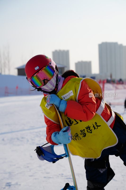 身穿滑雪服手持滑雪板的年轻女孩