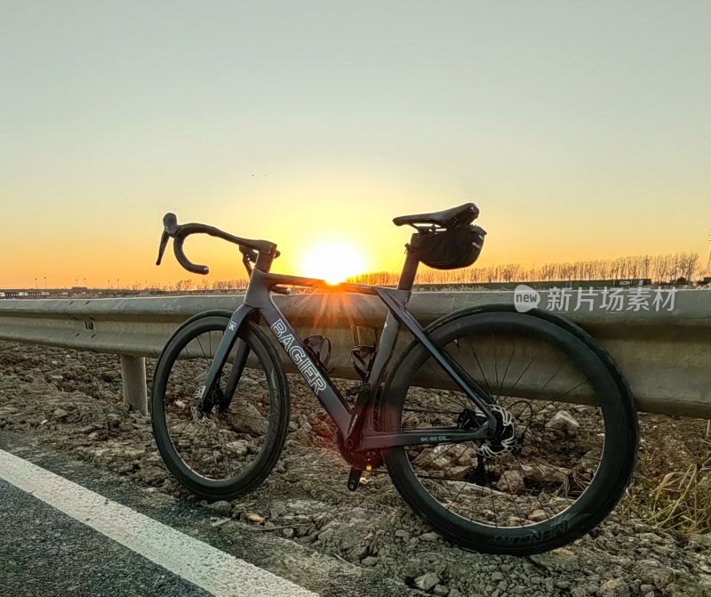 夕阳下靠在护栏边的公路自行车