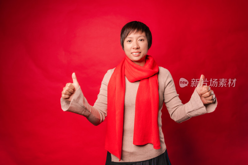 站在红色背景前竖大拇指的中国年轻女性