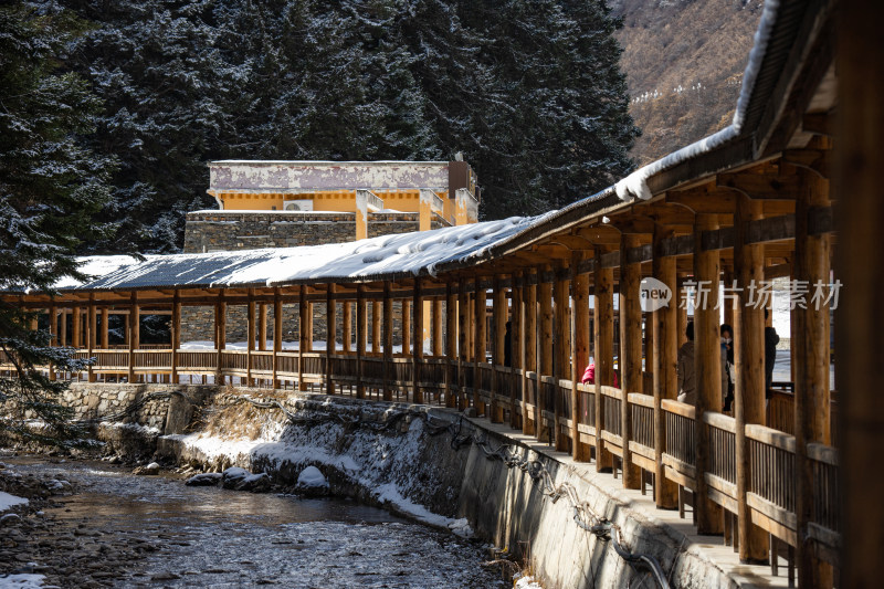 雪中木质长廊与山林小溪的冬日景象